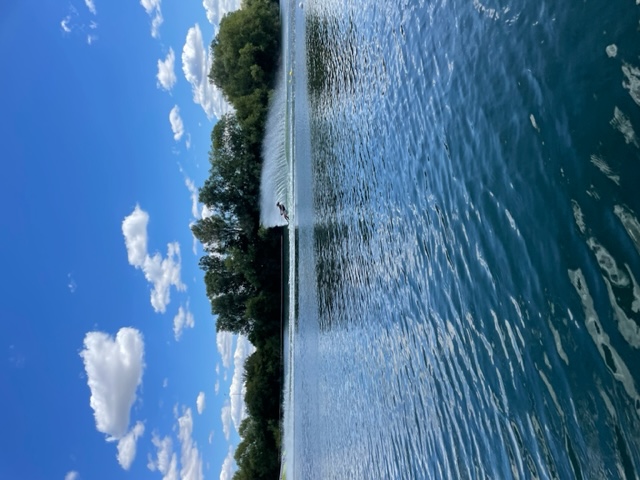 Person waterskiing in the distance, lots of water spray